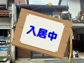 茶色の壁があり入り口が引き戸となっている2階建ての家屋の写真