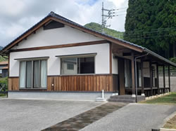 白い壁と茶色の板の外観を持ち縁側がある和風のおためし住宅の写真