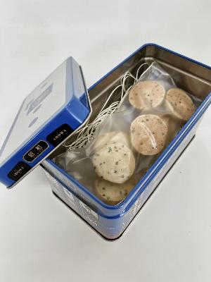 若桜鉄道『昭和号』列車缶入りえごまクッキーの蓋を開いてエゴマクッキーを見せた画像です。