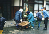 隣保館隣接の家屋の玄関前にて、門松作りに臨む町民たちの写真