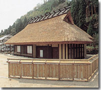 周囲に木の柵がある、山村の藁ぶき屋根の住宅の写真