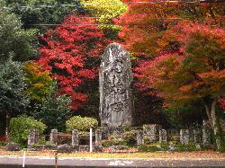 真っ赤に色付いた紅葉の木々に囲まれた、巨大な石碑の写真