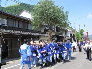 快晴の下、揃いの青い法被を着て歩く男性衆の写真