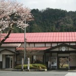 入り口に桜が咲いている若桜駅の駅舎の写真