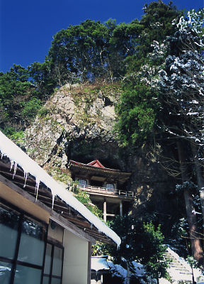雪解けの中、不動院岩屋堂に光がさしている写真