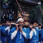 青い法被を着た男性たちが神輿を担いでいる写真