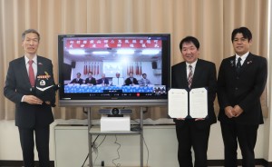 テレビの横に協定書を持って立っている向処長、矢部町長、鈴木観光交流局長の写真
