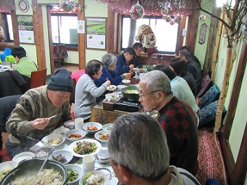 レストランで大人数がテーブルの周りに座って食事をしている写真