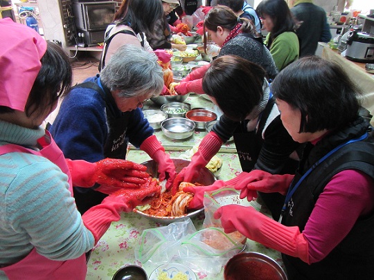 女性4人グループでテーブルの上でキムチを作っている様子の写真